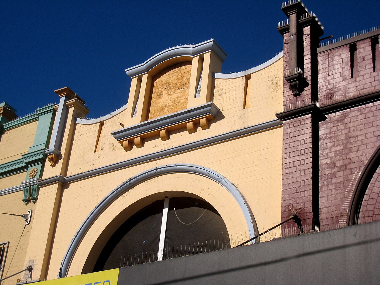 Upper storey facades of yellow and red brick heritage buildings on the Corso, arched window heads and painted parapets.