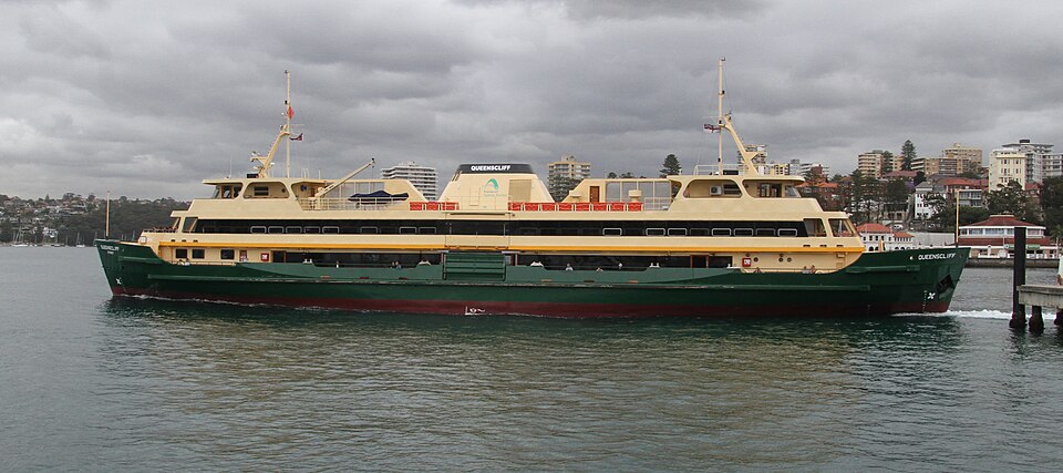 The Manly ferry Queenscliff crossing the harbour, green and cream hull, on the run the wharf still serves.