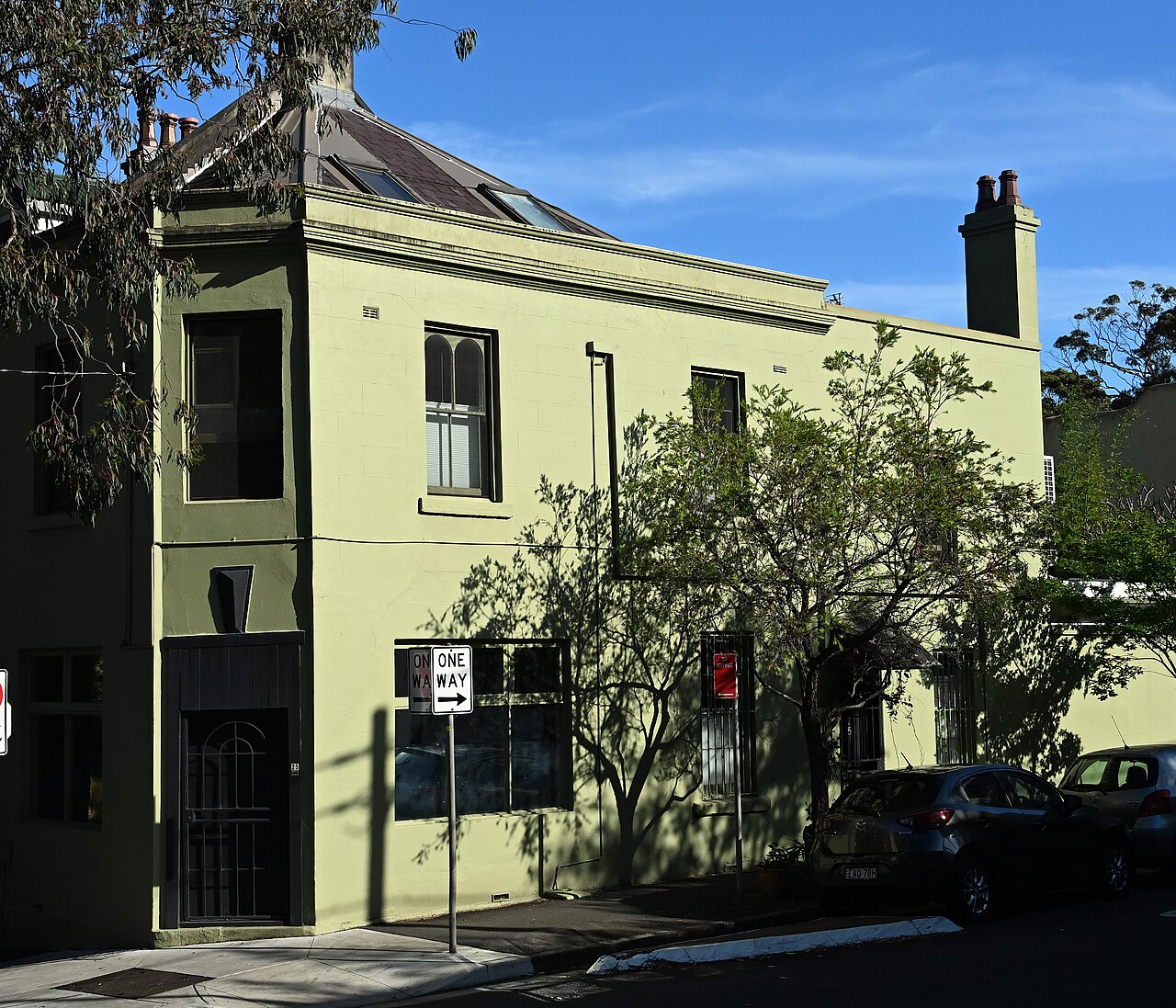 A narrow brick laneway behind the terraces, an ornate timber door with an iron grille and gold knockers set into a rendered wall.