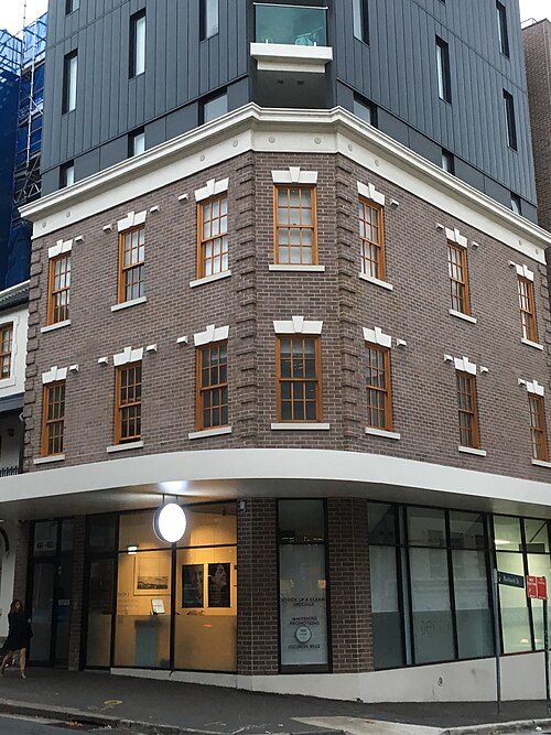 An orange rendered terrace building on Waterloo Street, a For Lease sign for a ground floor cafe or restaurant, an iron balcony over the footpath.
