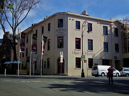 A three storey rendered pub on a street corner, Orient Hotel 1844 painted over the door, a delivery van at the kerb.