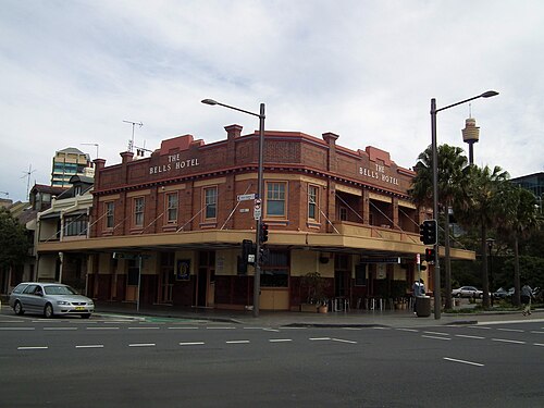 The Bells Hotel on its corner site, a two storey red brick pub with a continuous street awning and lettered parapet.