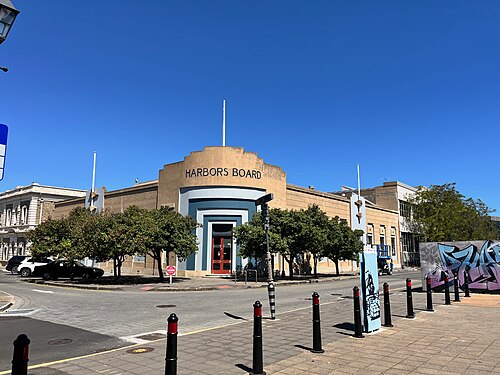 The Harbors Board building on McLaren Parade, an art deco corner block in cream and blue render with the name across the parapet and clipped trees along the footpath.
