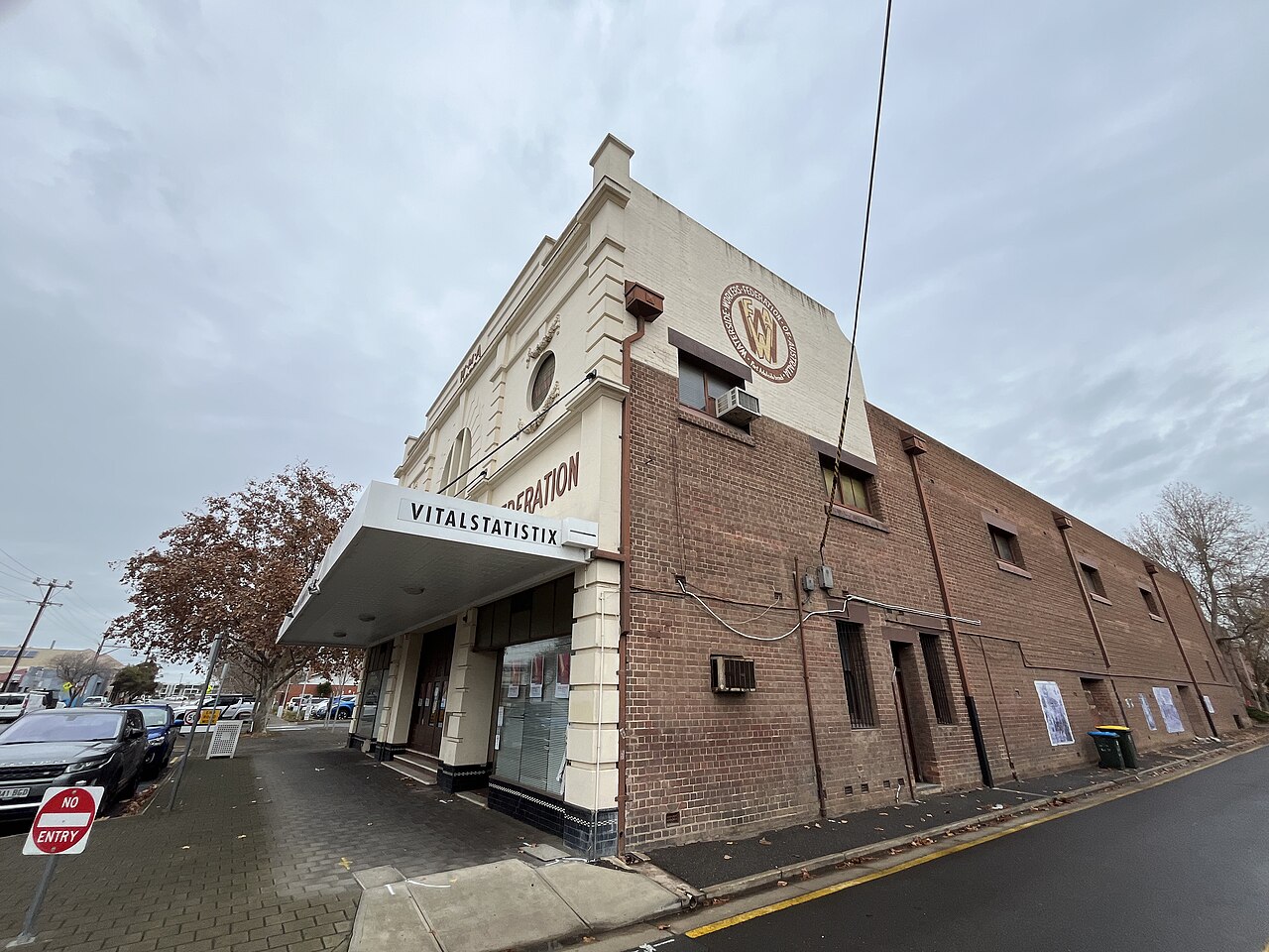 The Waterside Workers Federation building on Nile Street, a long brick side wall with small square windows and a rendered front, a Vitalstatistix sign under the awning.
