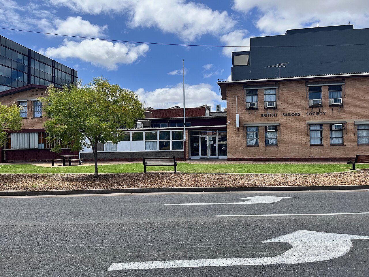 The former British Sailors' Society building, two storeys of brown brick with the name in metal letters and window air conditioners along the upper floor, seen across the road.