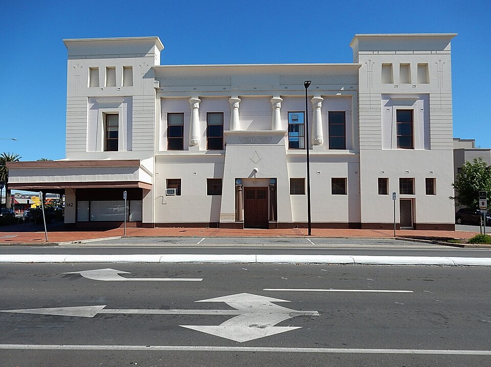 The Port Adelaide Masonic Centre from across Commercial Road, a white Egyptian revival front with two pylon towers, four lotus columns and the square and compasses above the door.