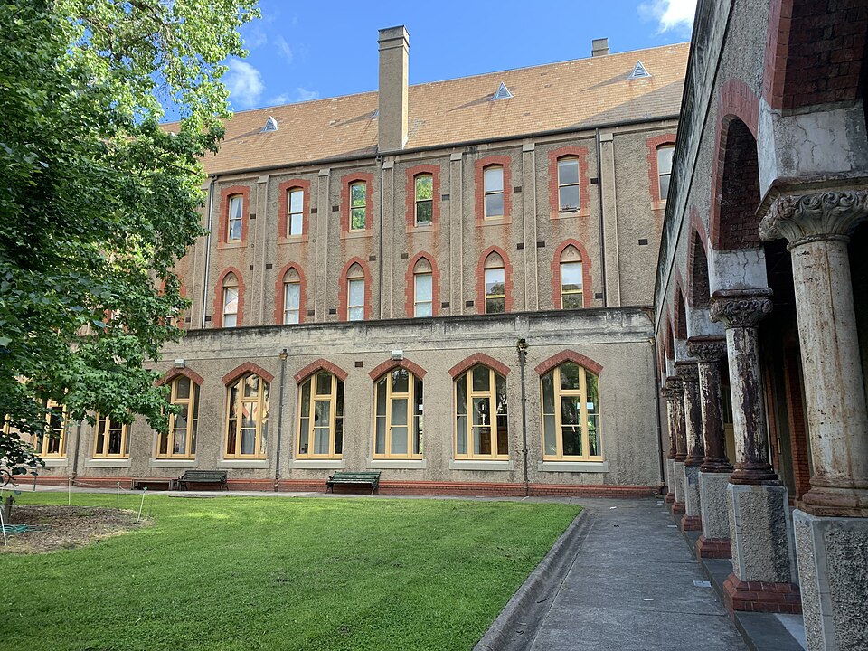 The convent's inner courtyard, a stone cloister of weathered columns and round arches running along the render and brick wing behind it.