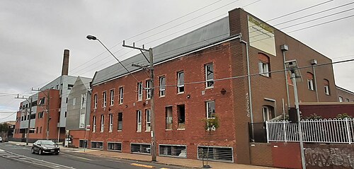 The former Hoffman Brickworks on Dawson Street, a multi storey red brick kiln building with its chimney stack behind.