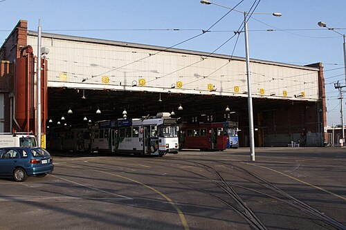 The corrugated metal shed of the Brunswick tram depot, several entrance bays wide, with trams parked inside.