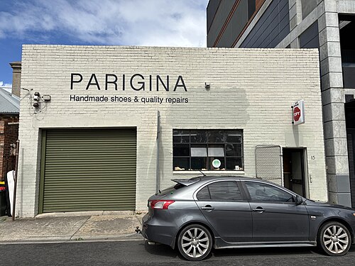 A single storey painted brick shoe repair shop with a roller door, a small working example of Brunswick's older industrial buildings.
