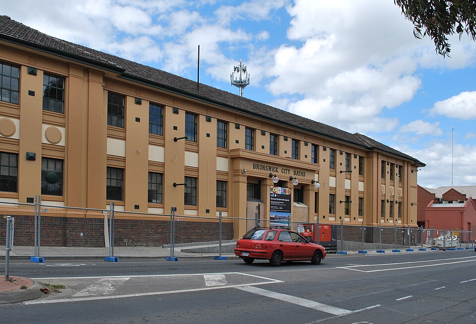 The Brunswick City Baths on the corner of Dawson Street and Sydney Road, a two storey stuccoed bathhouse with its name lettered above the entrance.