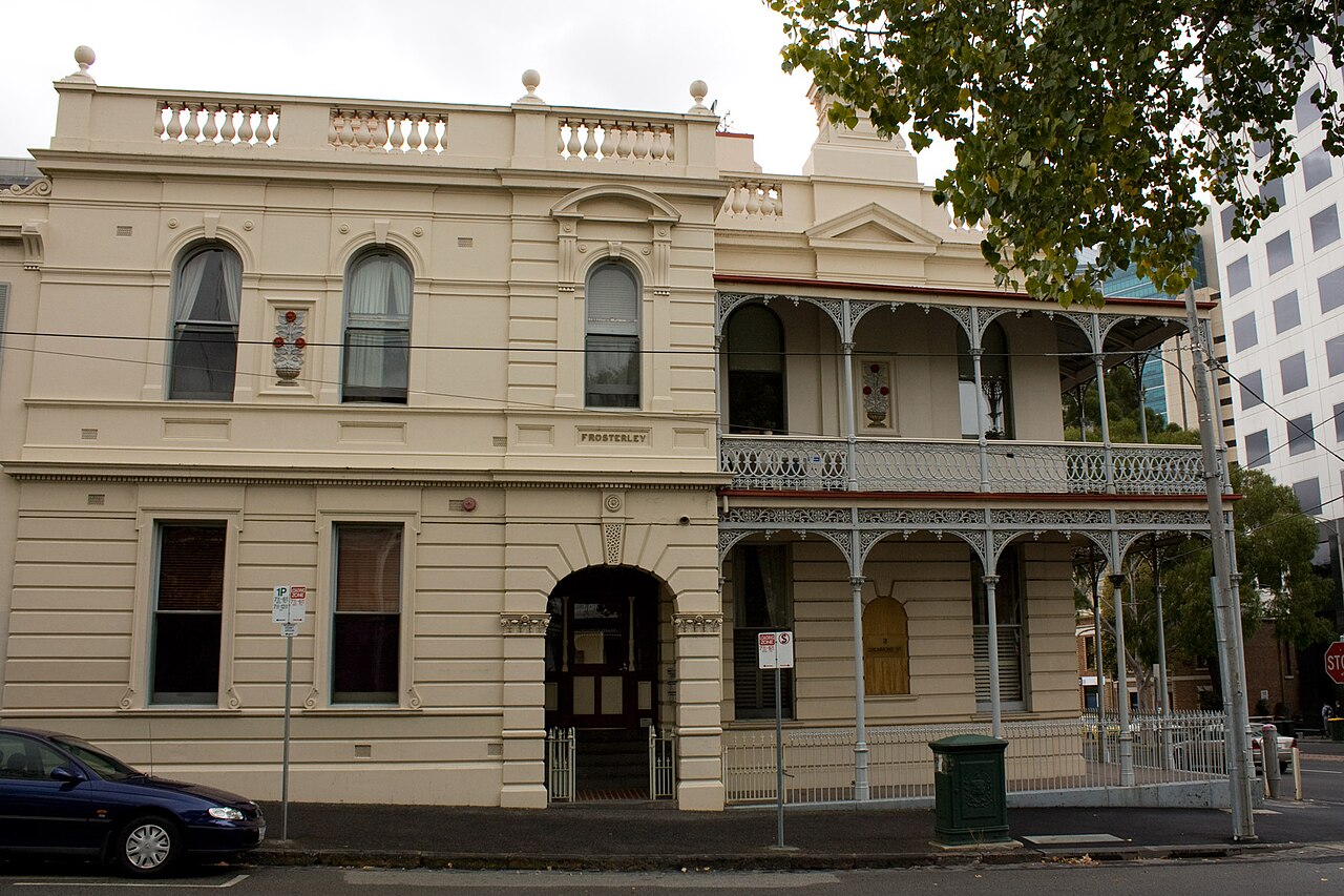 Frosterley House on Drummond Street, a two storey cream painted terrace with intricate cast iron lace verandahs, balustrades and arched windows.