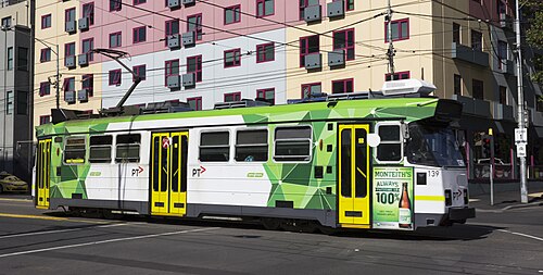 A tram on Swanston Street, overhead wires and a modern building behind it.