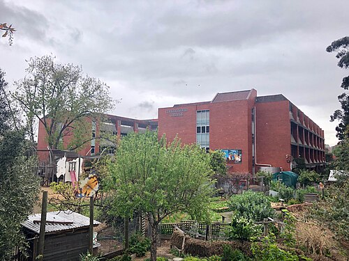 Collingwood College's red brick campus building behind garden trees.