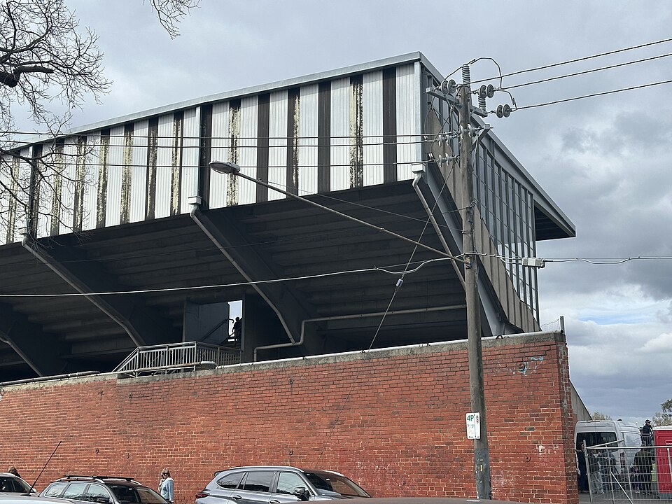 The back of the Sherrin Stand at Victoria Park, a red brick perimeter wall under a corrugated metal grandstand roof.