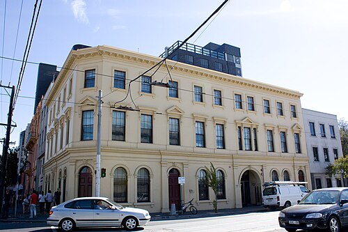 A three storey cream rendered corner building with arched ground floor windows at Brunswick Street and Victoria Parade, now part of the St Vincent's Hospital campus.