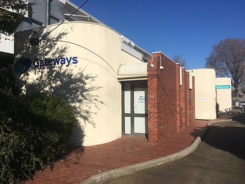 A low rise rendered office building with a curved cream wall and a red brick entrance section.