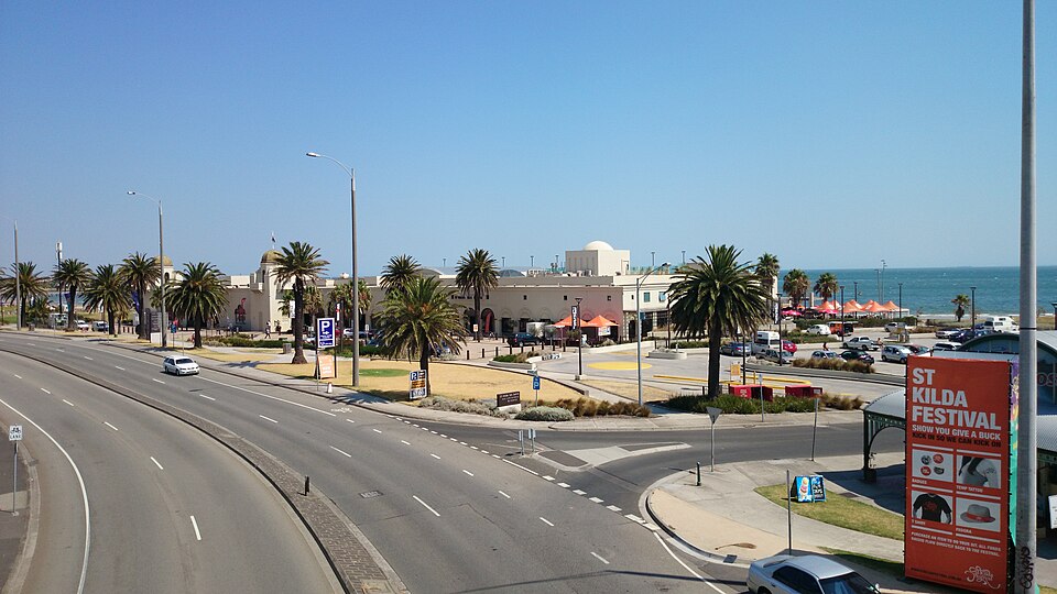 Jacka Boulevard's traffic lanes beside the St Kilda Sea Baths dome, palms along the footpath and the bay beyond.