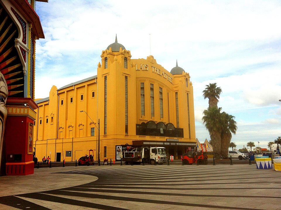 The Palais Theatre's wide yellow rendered facade under twin domed towers, PALAIS THEATRE lettered across the top above the entrance plaza.