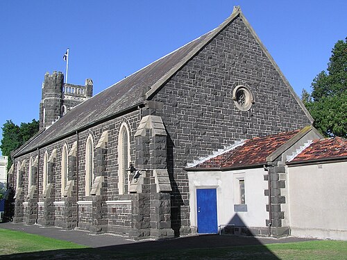 St Andrew's Presbyterian Church, a dark bluestone Gothic Revival building with buttresses and pointed arched windows.