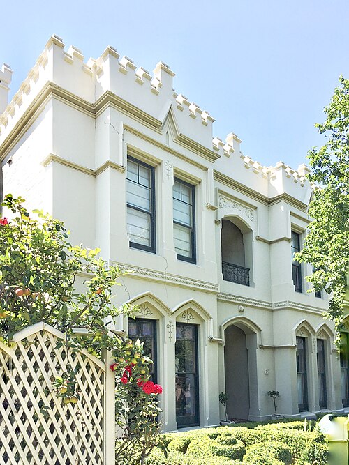 Tudor House on Pasco Street, a two storey cream rendered house with crenellated parapets and pointed arch windows.