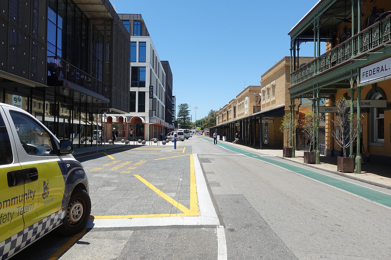 William Street seen south east from mid block, the Federal Hotel's cast iron verandah down the right hand side and a new dark glass building on the left, with floodlights at the far end.
