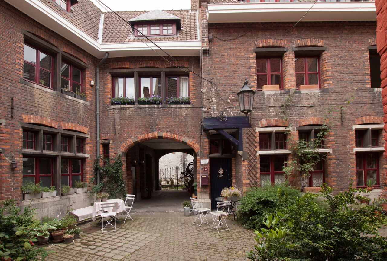 A beluik off the Plotersgracht, brick houses with red window frames around a paved courtyard, with an arched passage back out to the street.