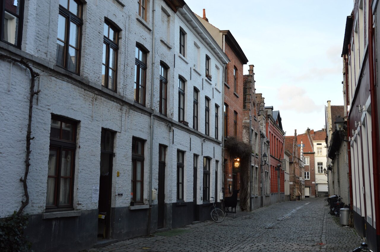 Corduwaniersstraat early in the morning, a long whitewashed brick terrace on the left and stepped gables further down on the right.