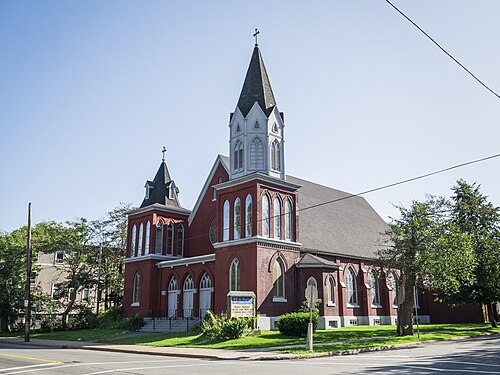 St. Mark's Church on the corner of Russell and Gottingen Streets, dark red brick with a white timber belfry and a black spire, a smaller tower to the left and a round window in the gable between them.