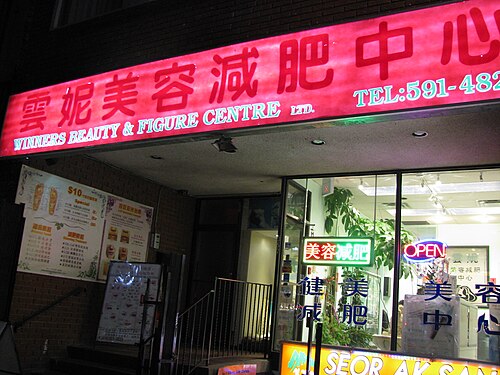 A red neon sign for Winners Beauty & Figure Centre lit up over a storefront at night, with an OPEN sign glowing in the window below it.