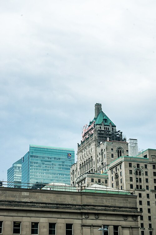 The green copper roof and stone tower of the Fairmont Royal York hotel, its sign reading Fairmont Royal York, beside a teal glass office tower marked RBC, with the stone cornice of Union Station in the foreground.