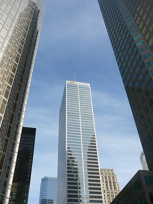 A white walled office tower marked CIBC rising between two darker glass towers, seen from street level looking straight up.