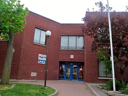 The brick entrance of Frankland Community Centre on Logan Avenue, with a pool sign mounted by the door.