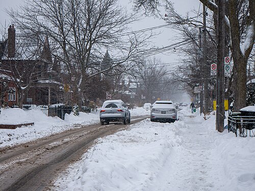 Logan Avenue under snow, a row of houses along the street and cars parked at the kerb.