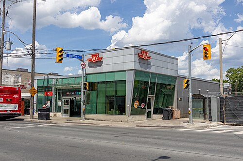 The Pape subway station entrance at street level, glass walls on the corner and the TTC roundel above the door.
