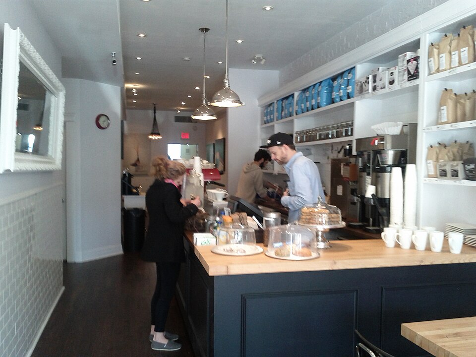The inside of a narrow storefront on Danforth Avenue, a counter along one wall and open shelving above it.