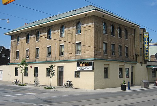 The New Edwin Hotel, a three storey brick corner building with arched upper windows, a nightclub sign mounted on the side wall and bicycles locked along the sidewalk.