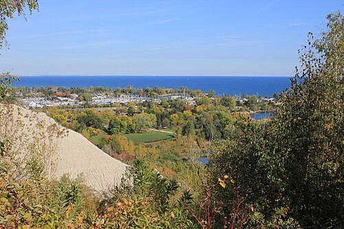 The view from the top of the bluffs down over Bluffer's Park marina, boats at their moorings and Lake Ontario stretching to the horizon, a strip of pale cliff visible at the left edge of the frame.