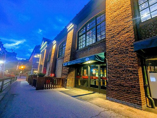 St. Lawrence Market's brick entrance at dusk, arched windows lit from inside above the St. Lawrence Market sign over the doors.