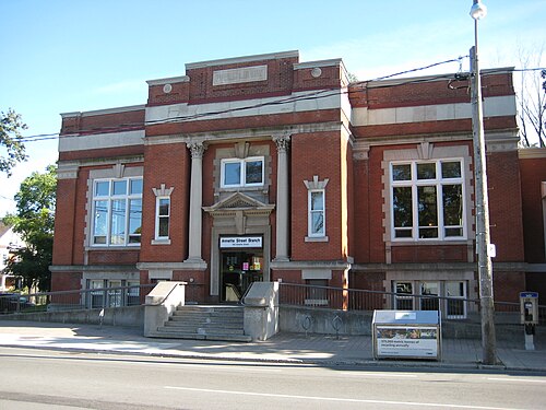 The Annette Street branch of the Toronto Public Library, a red brick Carnegie building with paired columns over the entrance and a stone panel above the roofline.