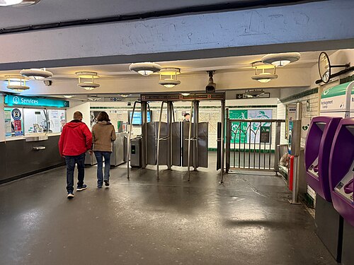 The ticket hall at Ménilmontant station on métro line 2, turnstiles across the middle, a staffed window on the left and the ticket machines along the right.
