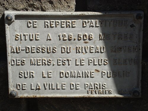 A cast plaque bolted to a stone wall on rue du Télégraphe. It says the level mark is 128.508 metres above mean sea level and the highest on the City of Paris's public land.