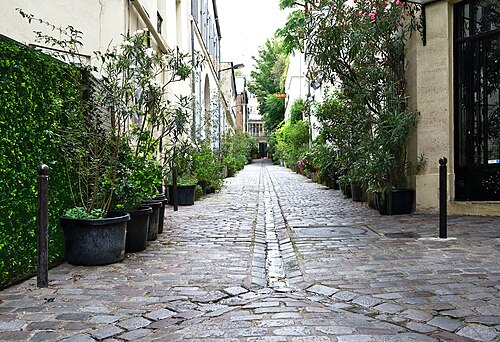 Cité du Midi, a cobbled alley off boulevard de Clichy lined with potted oleanders, with an old orange Bains sign on a wall part way down it.