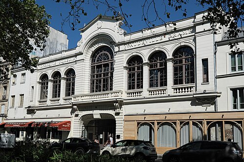 The front of Le Trianon at 80 boulevard de Rochechouart, a white theatre facade with tall arched windows, a balustrade and the words Opérette Comédie Vaudeville Drame cut into the stone.