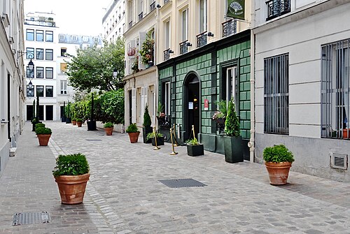 Cité Pigalle, a cobbled dead end with terracotta pots along it and a small hotel behind a green tiled front.