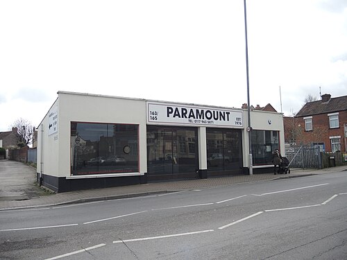 A small used car showroom on West Street, a single storey rendered building with a plain painted sign.