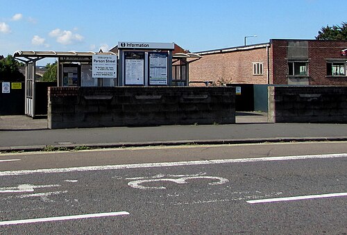 The entrance to Parson Street railway station off the A38, a glass shelter behind a low brick boundary wall.