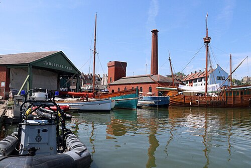 Underfall Yard's green painted shed and octagonal brick chimney, wooden sailing boats moored in front.