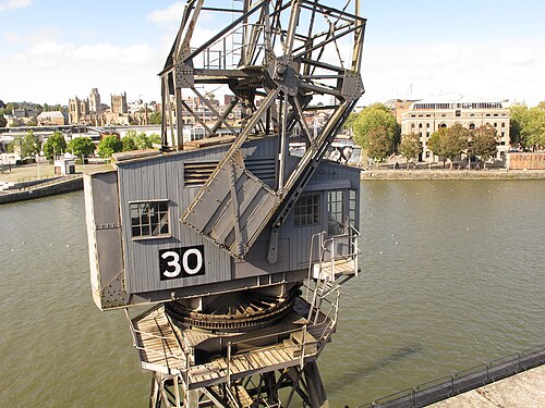 A close view of crane 30's cab and jib, the city's cathedral towers and the Arnolfini building visible across the water.