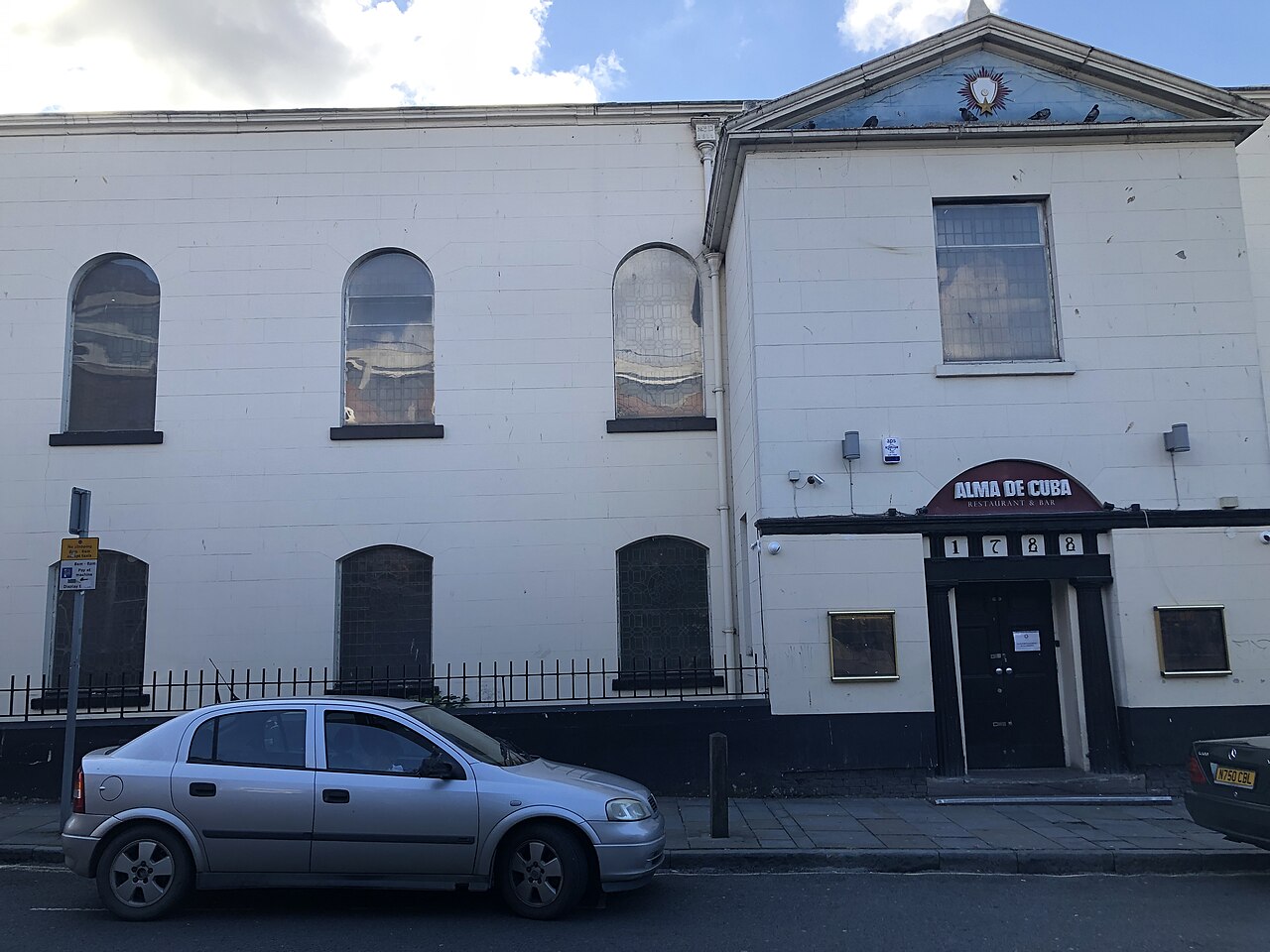 The former St Peter's on Seel Street, a white painted wall of round headed windows behind iron railings with 1788 over the door and the Alma de Cuba sign it carried until 2024.